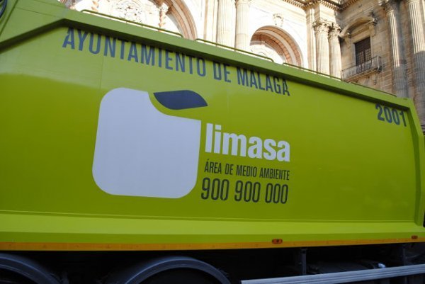 Сміттєзбиральна машина вже позаду колони, в яку працівники викидають сміття з баків, що стоять по вулиці і одразу замінюють сміттєві пакети на нові