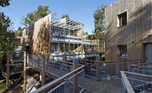 Житловий комплекс La Canopée (Франція). Будівлі комплексу «розставлені» серед дерев. Будинки стоять на опорах, під ними - парковки, сервісні зони і газони