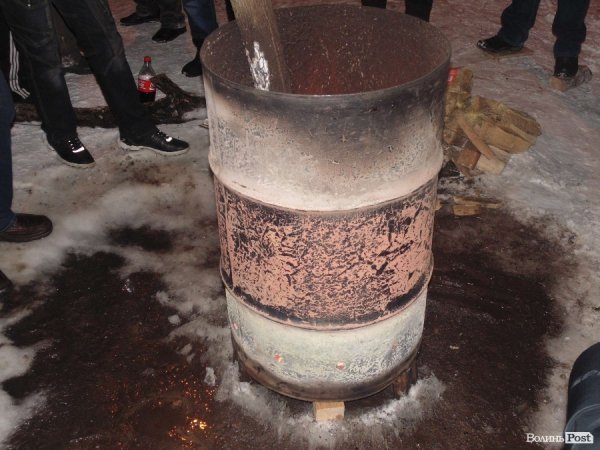 Люди гріються біля бочок з вогем