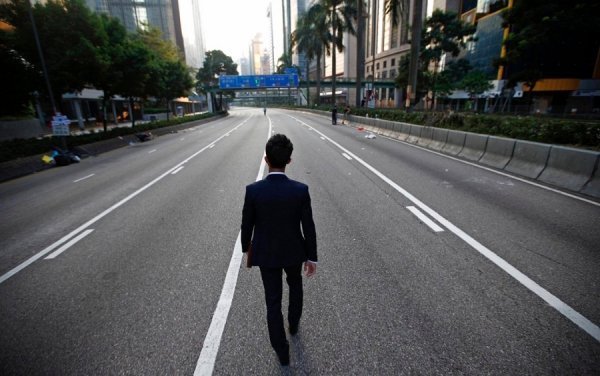 Чоловік іде безлюдною вулицею в районі фінансового центру Гонконгу, де десятки тисяч активістів демократичного руху проводять акції протесту. (© Reuters)