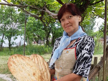 У селі на Волині жінка пече азербайджанський хліб в тандирі