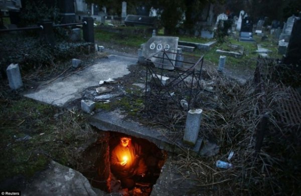 Сербський безхатько Братислав Стоянович тримає свічку в могилі, де він живе. Стоянович оселився на кладовищі міста Ніш близько п'ятнадцяти років тому