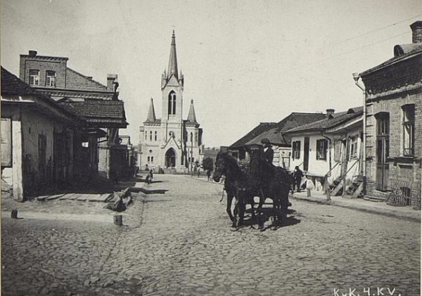 Забрукована вулиця Кафедральна. Видно, що проїзну частину відділили від тротуарів підвищенням. Біля цього підвищення виникає канавка для стікання води. Фото з Австрійської національної бібліотеки