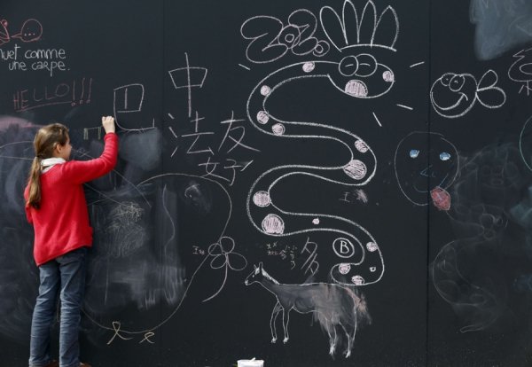 Дівчина малює крейдою на набережній (Париж, Франція)