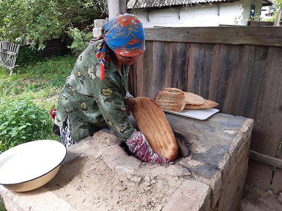 У селі на Волині жінка пече азербайджанський хліб в тандирі