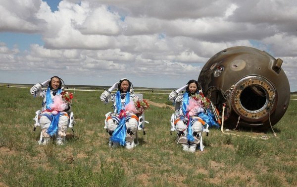 13. Китайські космонавти салютують біля капсули з Шеньчжоу після вдалого приземлення в Монголії