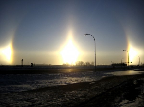 Це неймовірне явище відоме як паргелій і виникає воно тоді, коли сонячні промені заломлюються в кристалах льоду, які знаходяться в атмосфері