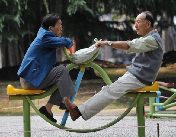 Літня пара катається на гойдалці в парку