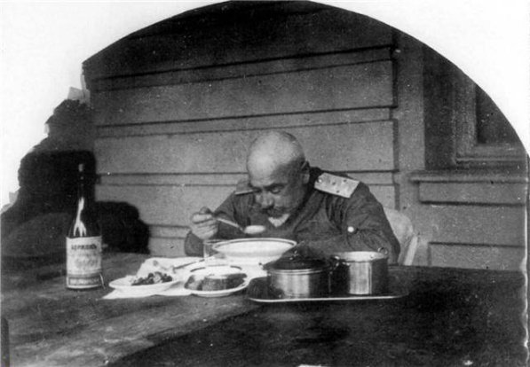 Генерал Денікін пробує їжу на благодійному обіді, фото для пропагандистської преси. На столі пляшка мінеральної води «Боржомі».
