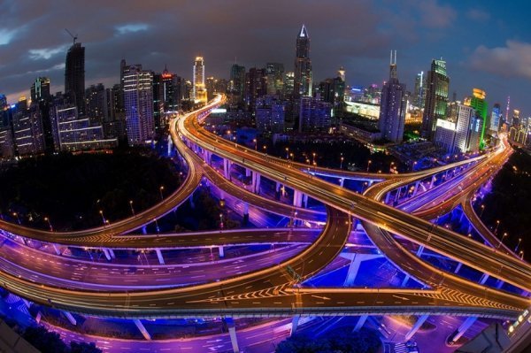 На фотографії з довгою витримкою зображено автомобільний рух на дорогах в годину пік, напередодні Національного дня в Шанхаї. (© AFP)