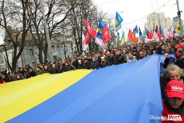 Під час акції опозиції мітингарі несуть великий стяг