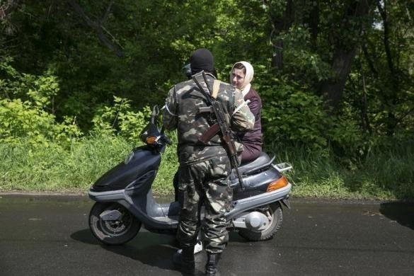 озброєний сепаратист розмовляє  з жінкою, яка приїхала  на скутері до КПП неподалік Слов'янська
