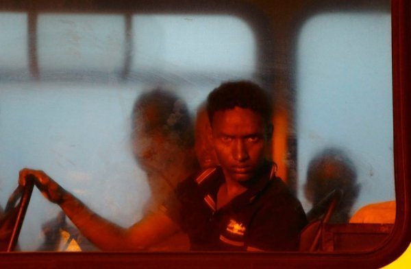 Біженець виглядає з вікна в поліцейському автобусі після прибуття на Мальту, 10 липня 2013. DARRIN ZAMMIT LUPI, Мальта